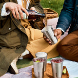 A close up of a couple of adults having a picnic and pouring drink into the Black + Blum stainless steel cups 