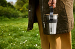 A close up of an adult holding the Black + Blum stainless cup set by the handy black strap handle