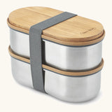 Angled Black+Blum two 500ml stainless steel leakproof boxes with a bamboo lid/chopping board and nylon strap