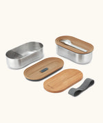 An open Black+Blum 500ml stainless steel leakproof bento box showing a fork and bamboo lid/chopping board