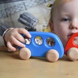 A child's hand pushing a blue coloured Bajo bus on a Triclimb Miri board. These heirloom quality toys by Bajo are part of a wide range of wooden toys available here at Babipur. 