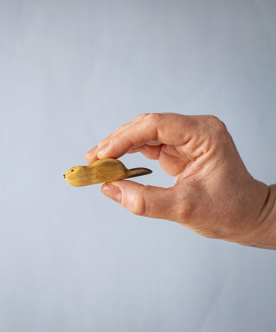 A hand holding the Bumbu wooden beaver figure 