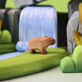 Bumbu Toys Wooden Baby Capybara in a scene with Bumbu rocks and grass.