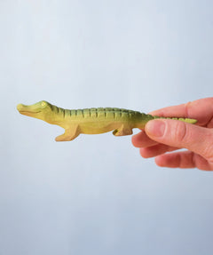 Bumbu Roys' Wooden Baby Crocodile, being held in an adult's hand.