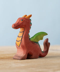 Bumbu Toys handmade wooden Baby Dragon figureplaced on a wooden surface. 