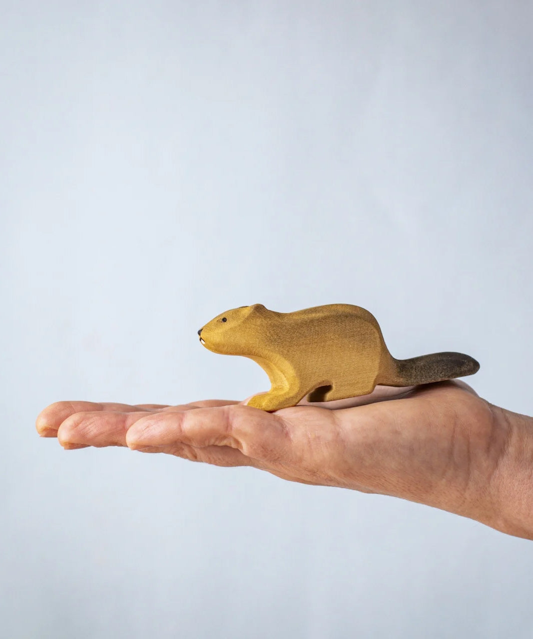 A hand holding the Bumbu wooden beaver figure