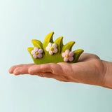 Adult hand holding a Bumbu wooden blossom bush figure showing scale