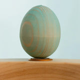 Bumbu wooden hand painted festive blue egg decorative figure standing in a celebration ring with a blue background