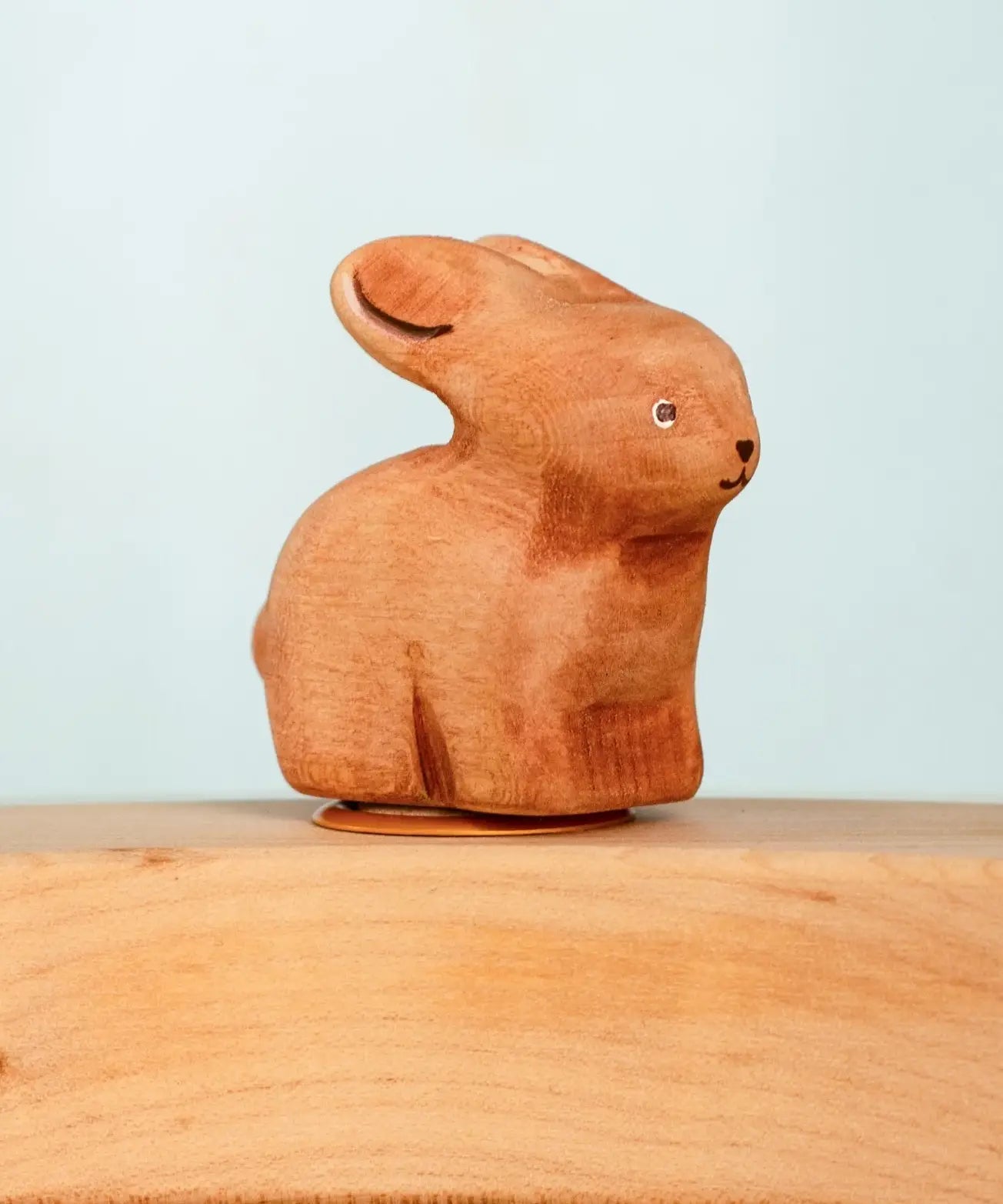 Bumbu wooden hand painted brown bunny decorative figure standing in a celebration ring against a blue background