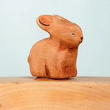 Bumbu wooden hand painted brown bunny decorative figure standing in a celebration ring against a blue background