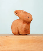 Bumbu wooden hand painted brown bunny decorative figure standing in a celebration ring against a blue background