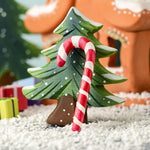 A red and white wooden Bumbu candy cane resting on the small Bumbu Christmas tree