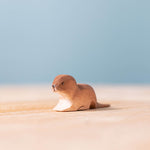 Close up of the Bumbu handmade wooden baby otter toy on a wooden suface