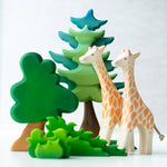 2 Ostheimer giraffe figures on a white background next to a Bumbu wooden Spruce tree and shrub bush toys