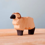 Bumbu handmade wooden standing ram animal figure on a wooden worktop in front of a blue background
