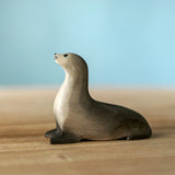 Bumbu curious harp seal wooden toy figure placed on a wooden surface.