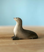 Bumbu curious harp seal wooden toy figure placed on a wooden surface.
