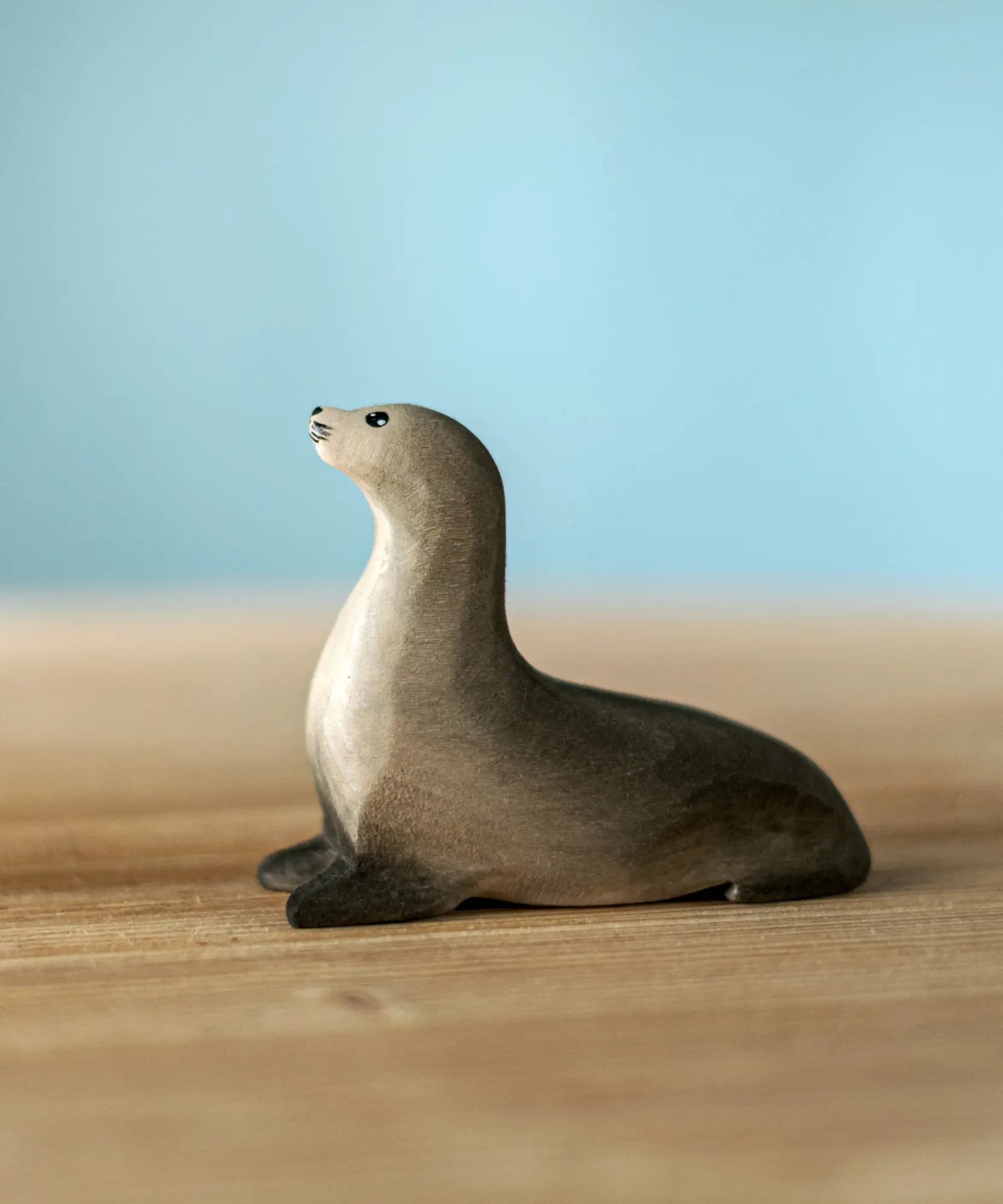 Bumbu curious harp seal wooden toy figure placed on a wooden surface.