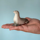 Bumbu curious harp seal wooden toy figure in an adult's hand.