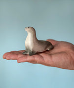 Bumbu curious harp seal wooden toy figure in an adult's hand.