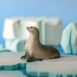 Bumbu curious harp seal wooden toy figure placed on an ice piece in a small world play scene.