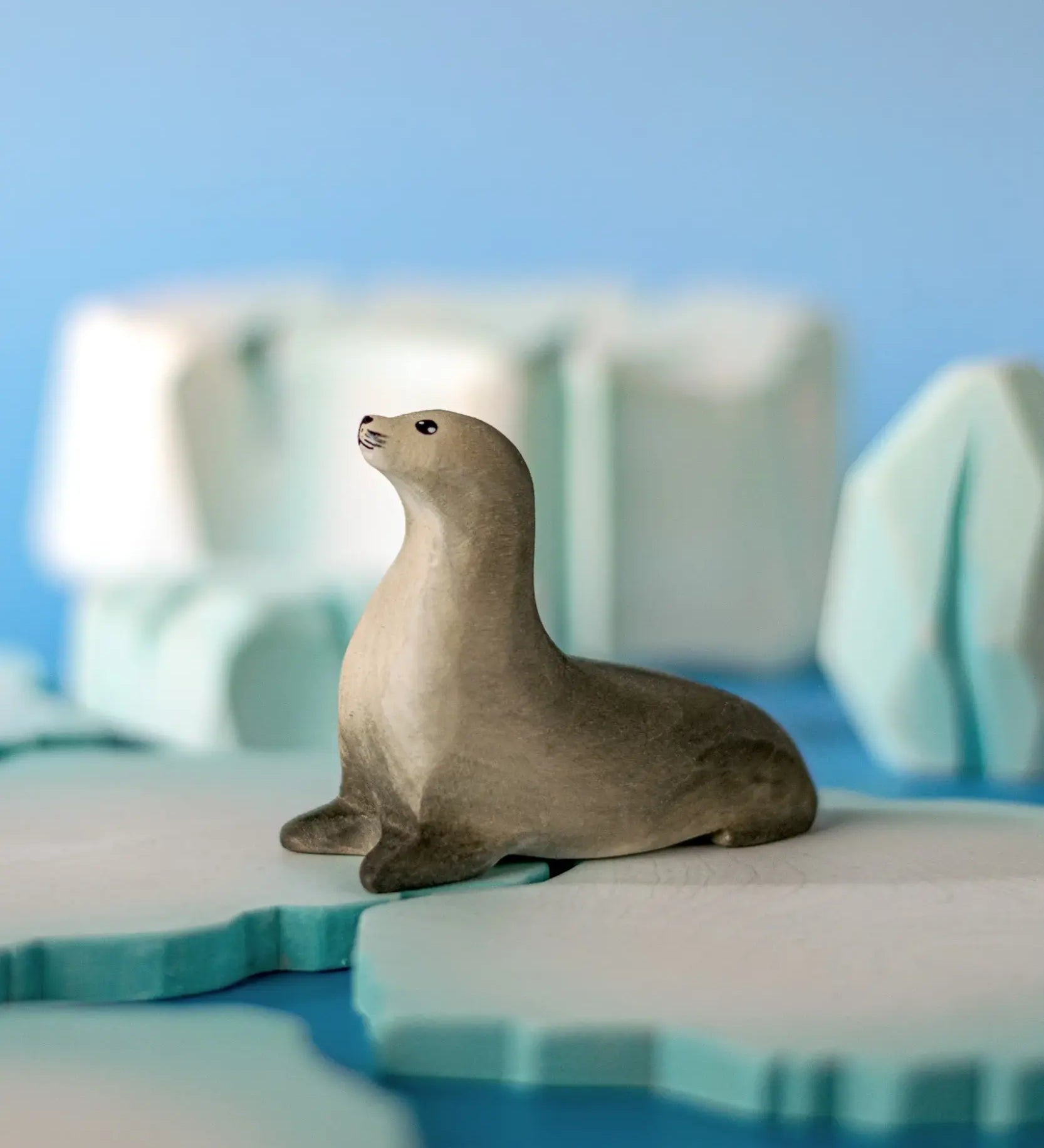 Bumbu curious harp seal wooden toy figure placed on an ice piece in a small world play scene.
