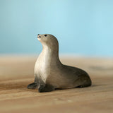 Bumbu curious harp seal wooden toy figure placed on a wooden surface.