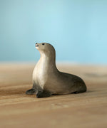 Bumbu curious harp seal wooden toy figure placed on a wooden surface.