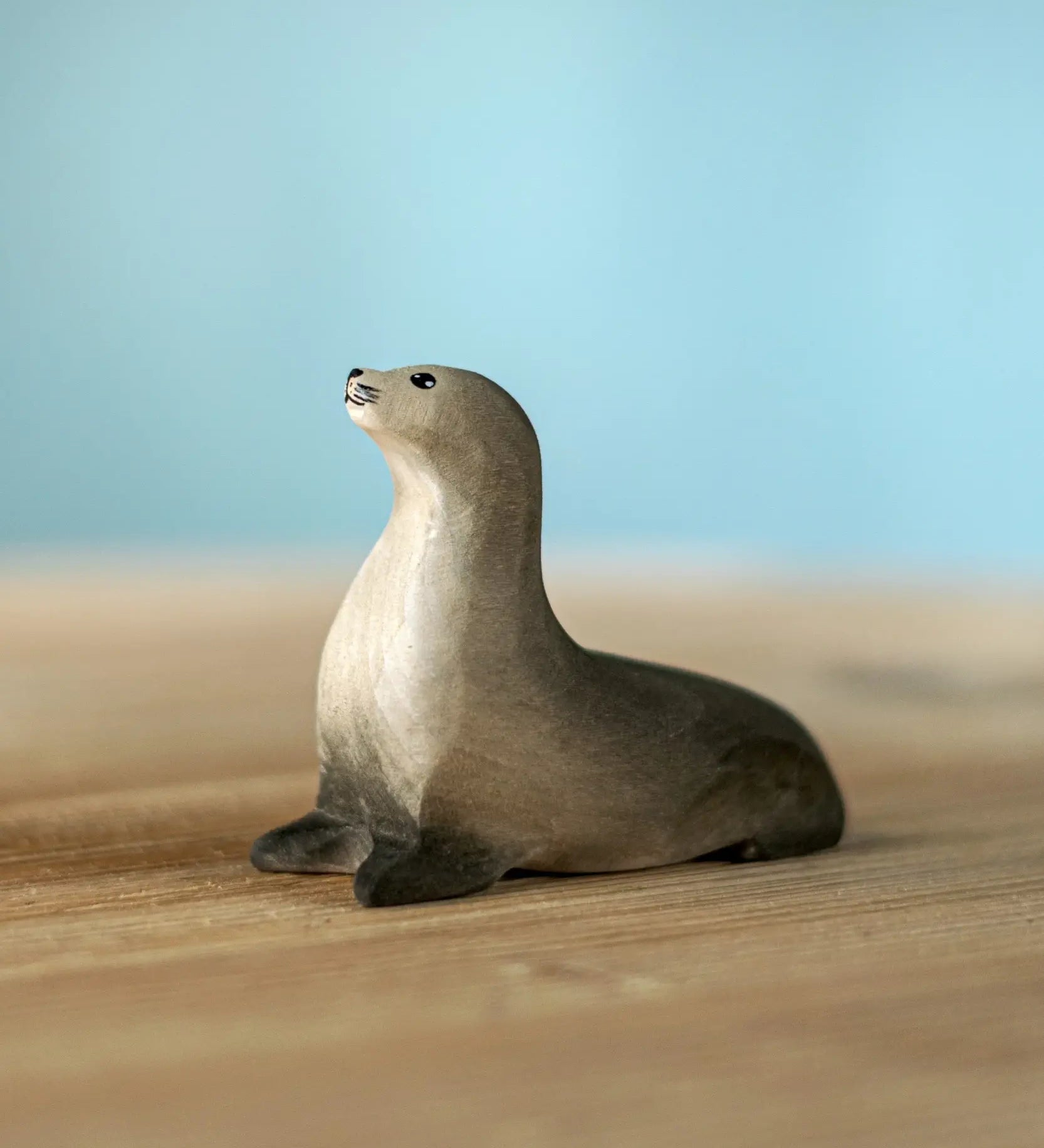 Bumbu curious harp seal wooden toy figure placed on a wooden surface.
