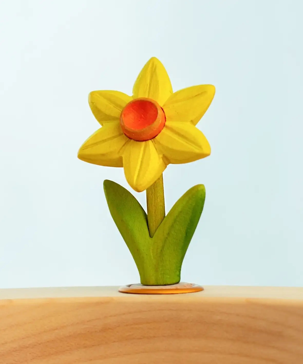 Bumbu wooden hand painted yellow festive daffodil decorative figure standing in a celebration ring against a blue background