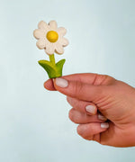 Adult hand holding the Bumbu handcrafted wooden daisy decorative figure showing size