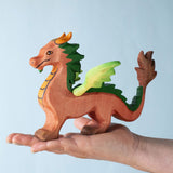 A Bumbu Toys handmade red dragon figure placed on the palm of an adult's hand to show scale. 