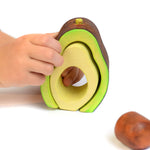 Close up of hands playing with the Bumbu plastic free wooden avocado stacking toy on a white background