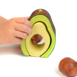 Close up of hands playing with the Bumbu plastic free wooden avocado stacking toy on a white background