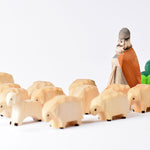 Bumbu eco-friendly wooden shepard with beard figure behind a flock of wooden sheep toys on a white background