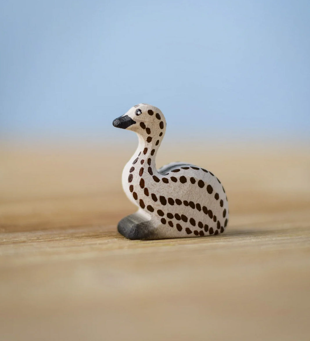 Bumbu wooden sitting emu chick resting on a wooden board.