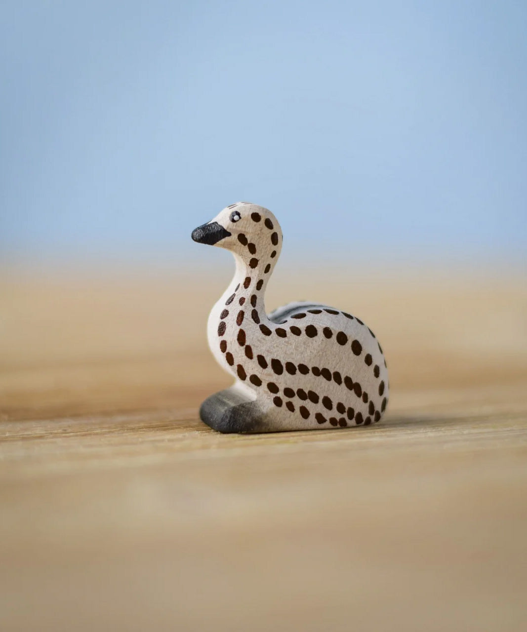 Bumbu wooden sitting emu chick resting on a wooden board.