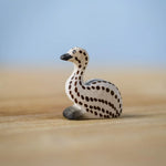 Bumbu wooden sitting emu chick resting on a wooden board.