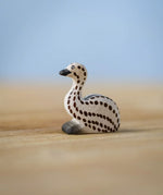 Bumbu wooden sitting emu chick resting on a wooden board.