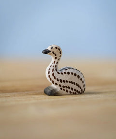 Bumbu wooden sitting emu chick resting on a wooden board.