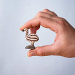 A hand holding the Bumbu wooden emu chick figure