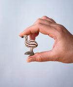 A hand holding the Bumbu wooden emu chick figure