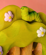 Bumbu caterpillar resting on top of the Bumbu toys wooden fairy treehouse 
