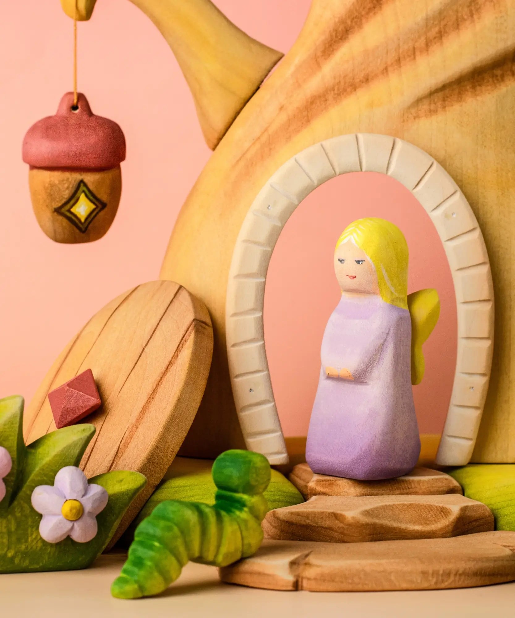 Bumbu pink fairy standing inside the doorway on the Bumbu fairy treehouse next to the hanging lantern and caterpillar figure 