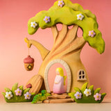 Bumbu wooden fairy treehouse with a pink fairy figure standing in the doorway with wooden blossom bushes either side