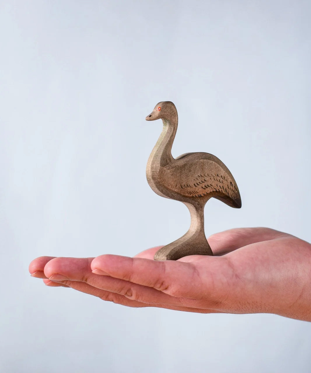 A hand holding the Bumbu wooden female emu 