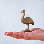 A hand holding the Bumbu wooden female emu 