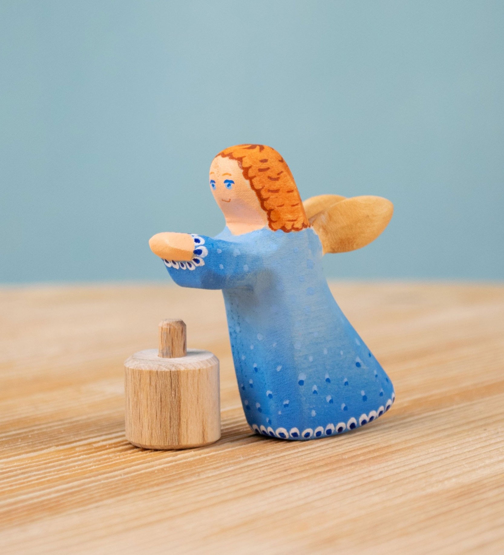 Bumbu blue Festive Angel Celebration decorative Figure to fit on a Grimm's celebration ring. The figure is shown separated from it's wooden base piece. These festive figures are perfect for your Christmas celebration ring set up. These expertly hand crafted items are part of a large range of wooden toys and decorative figures available here at Babipur. 