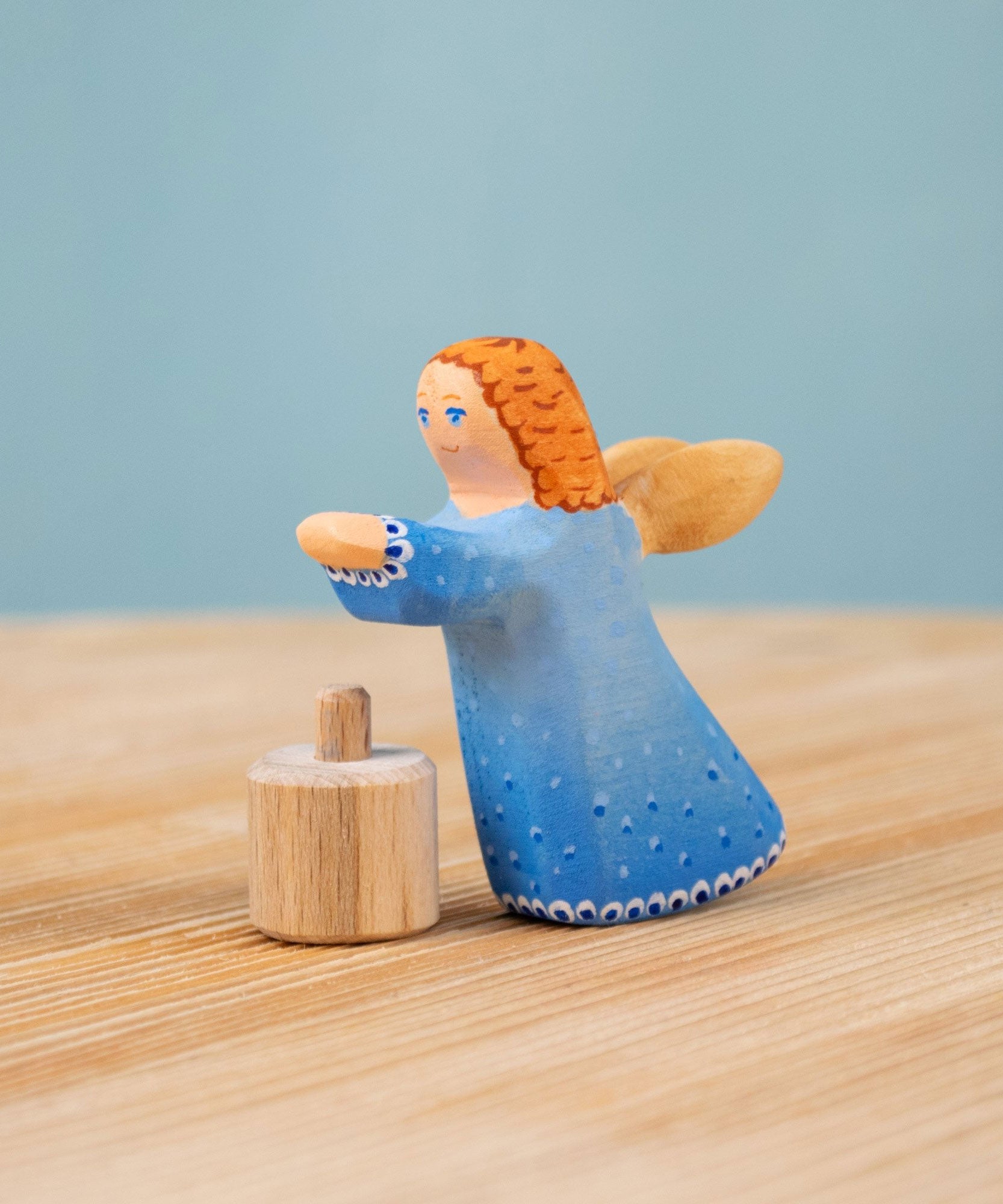 Bumbu blue Festive Angel Celebration decorative Figure to fit on a Grimm's celebration ring. The figure is shown separated from it's wooden base piece. These festive figures are perfect for your Christmas celebration ring set up. These expertly hand crafted items are part of a large range of wooden toys and decorative figures available here at Babipur. 