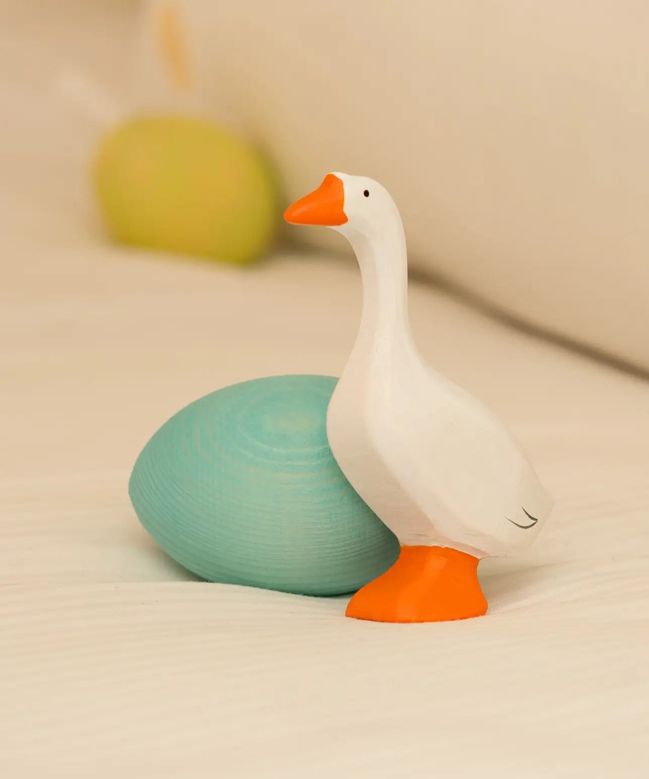 Bumbu handcrafted wooden white goose figure standing next to to a blue egg decorative figure